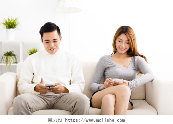 快乐的年轻夫妇在沙发上看手机